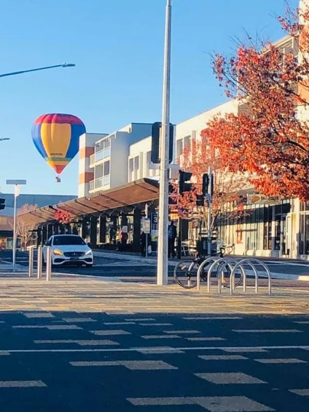 Colorful hot air balloon in a city street with autumn trees.