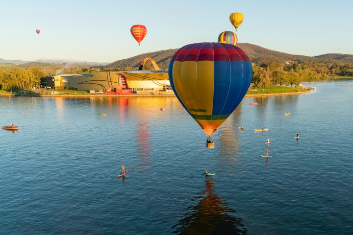 a group of people flying kites in a large body of water